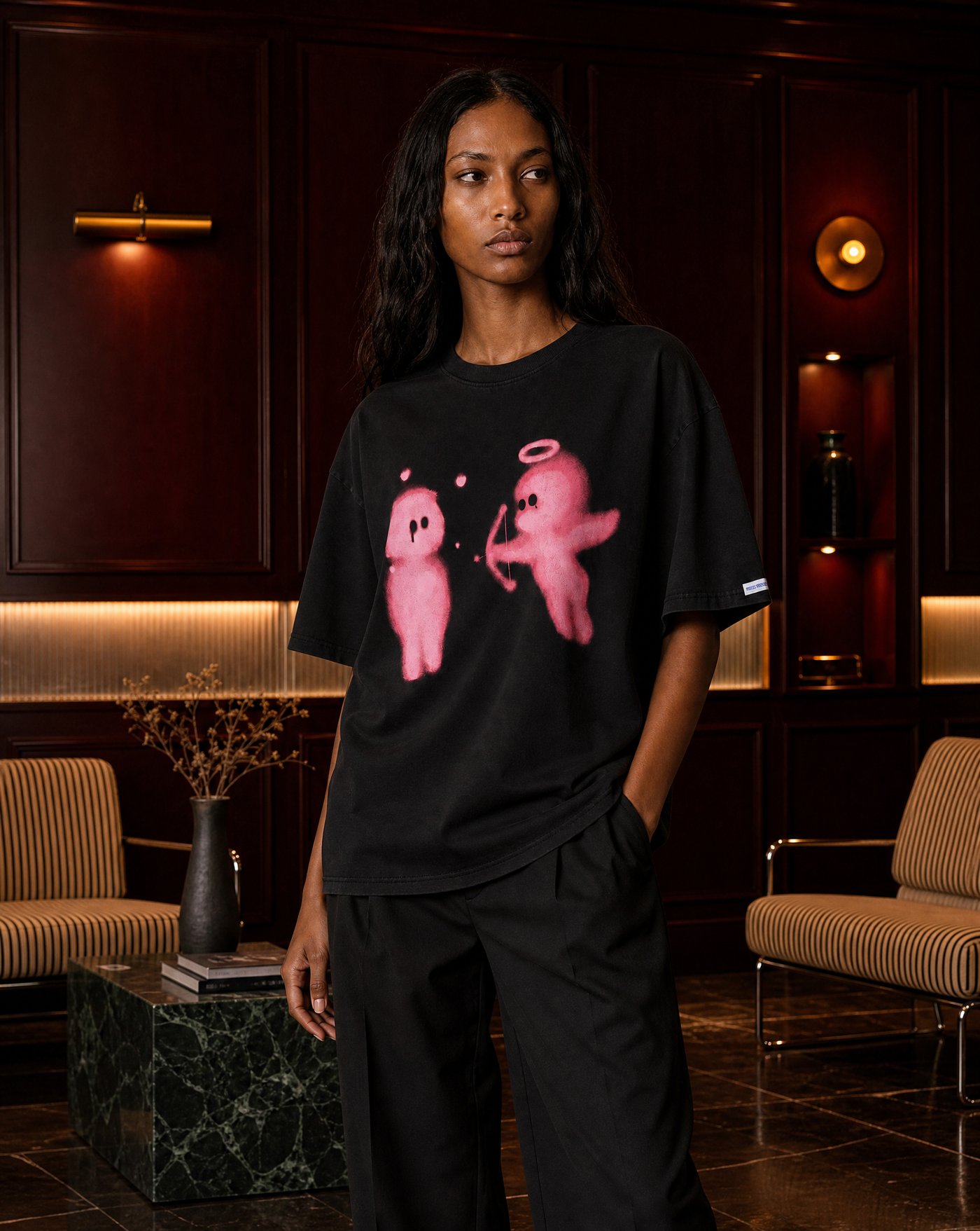 Model wearing the Cupid Arrow Tee in a dark wood-panelled lounge - editorial